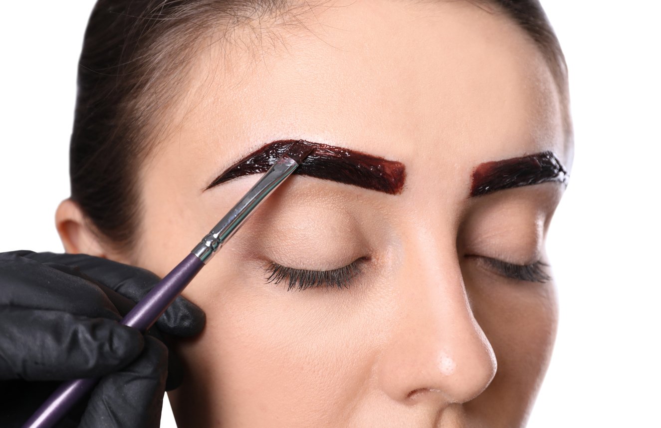 Beautician Applying Tint during Eyebrows Correction Procedure on